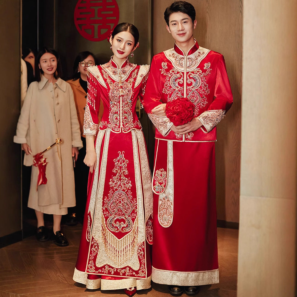 Bride and groom in matching Imperial Phoenix Chinese wedding attire with gold embroidery, posing together at venue entrance.