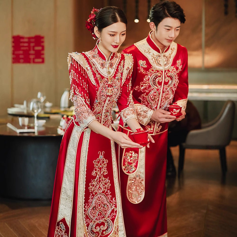 Bride and groom in Imperial Phoenix wedding outfits performing Chinese tea ceremony in elegant modern venue.