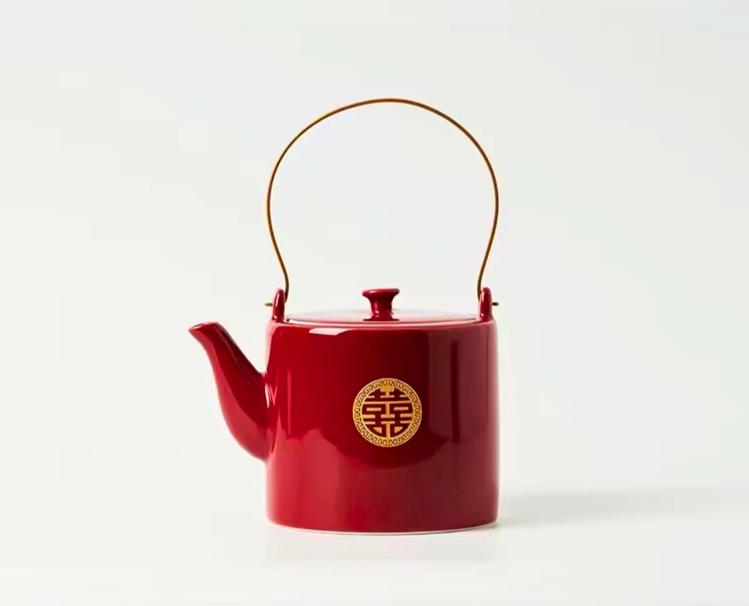 Red teapot with a gold emblem on a white background