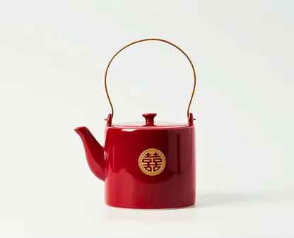 Red teapot with a gold emblem on a white background
